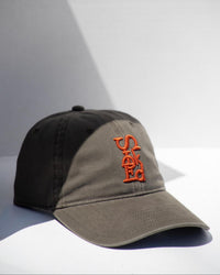 Two-tone cap with orange logo on a light gray background