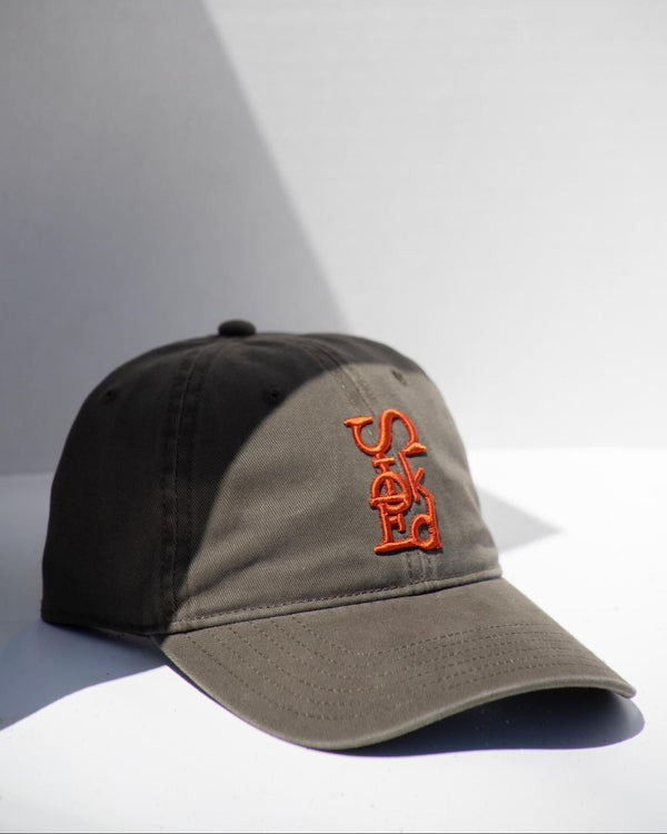 Two-tone cap with orange logo on a light gray background